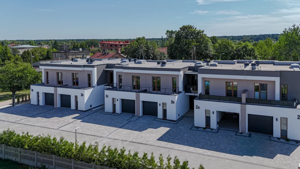 Całe osiedle szeregowe 2A-2E z lotu ptaka, płaskie dachy i podjazd z kostki, panorama okolicy