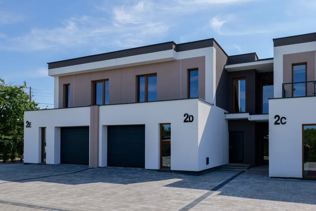 Bryła segmentów 2C-2DE z płaskim dachem, narożne ujęcie elewacji w mocnym świetle dziennym