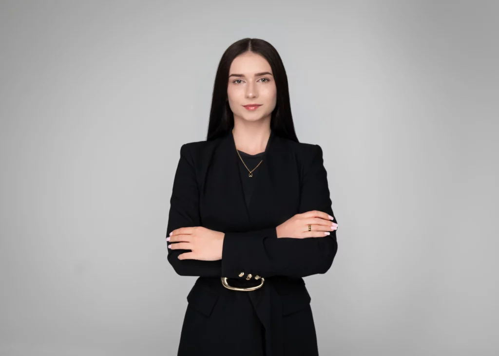 Portret biznesowy en face kobiety w czarnym żakiecie ze skrzyżowanymi rękami, jasne lto studyjne