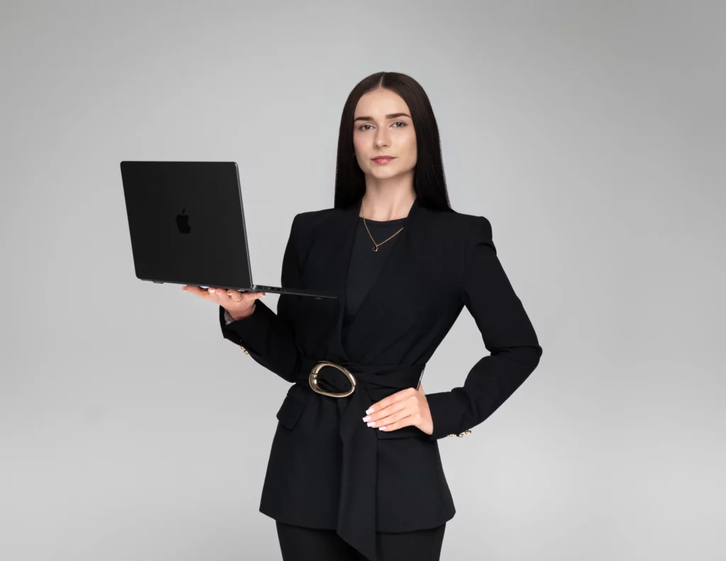 Kobieta w czarnym garniturze trzymająca laptop - portret biznesowy na jasnym tle